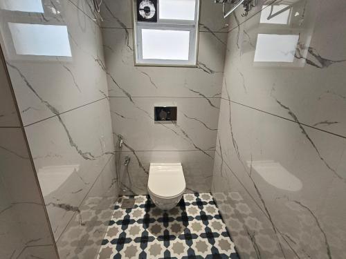 a bathroom with a toilet and a black and white tile floor at Hotel Prime Suites Airoli in Navi Mumbai