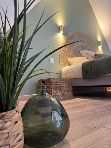 a vase on a table in a room with a bed at Gîte de brocottes in Hotot-en-Auge