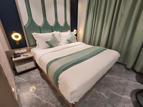 a bedroom with a large bed with a green headboard at Hotel Prime Suites Airoli in Navi Mumbai