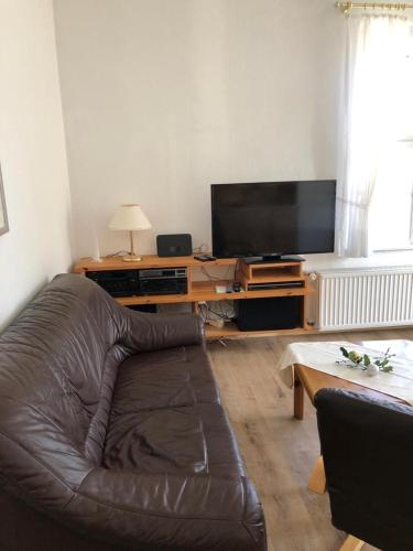 a living room with a leather couch and a flat screen tv at Hotel Carlsruh in Braunlage