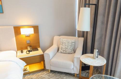 a room with a chair and a bed and a lamp at Hotel Skypark Central Seoul Pangyo in Seongnam