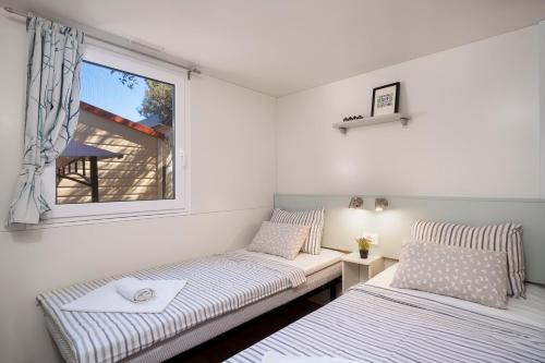 two beds in a room with a window at NIKO Mobile Home in Biograd na Moru
