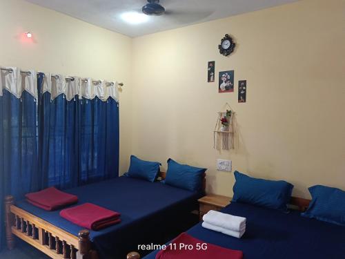 two beds in a room with blue curtains at Srujana Beach Homestay in Gokarn