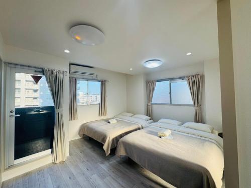 ein Schlafzimmer mit zwei Betten und einem großen Fenster in der Unterkunft LOFT-Hatsudai hostel初台SY0362 in Tokio