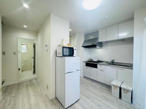 eine Küche mit einem weißen Kühlschrank und einer Mikrowelle in der Unterkunft LOFT-Hatsudai hostel初台SY0362 in Tokio