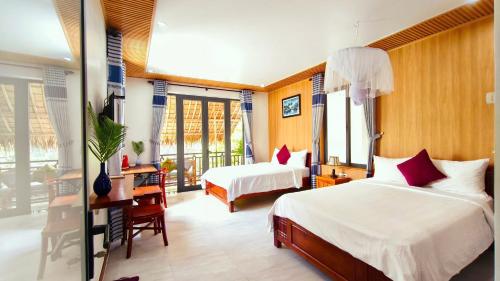a hotel room with two beds and a desk and windows at An Bang Star Homestay in Hoi An