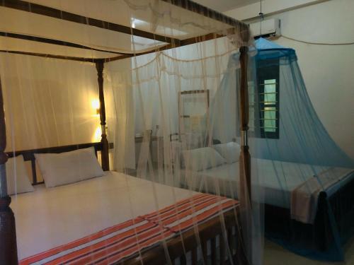 a bedroom with a canopy bed with white pillows at Calm Garden Cabanas in Tangalle