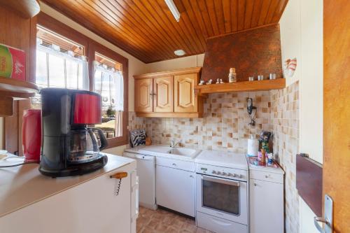 une cuisine avec des appareils électroménagers blancs et des armoires en bois dans l'établissement Gîte - Les Pessettes - Vue Montagne, à Prénovel