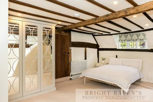 a bedroom with a white bed and a wooden ceiling at Old Manor House, an idyllic country house in Shabbington