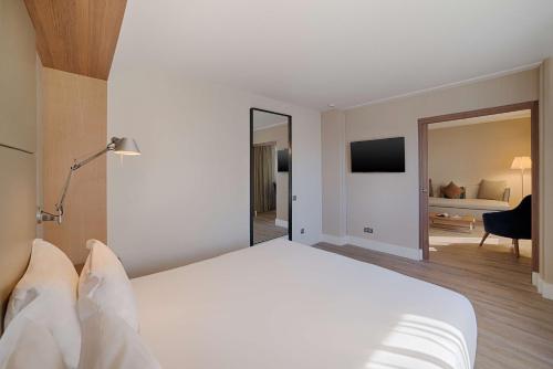 a hotel room with a large white bed and a living room at NH Nice in Nice