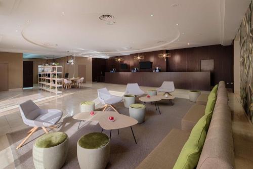 a lobby with a couch and tables and chairs at NH Nice in Nice