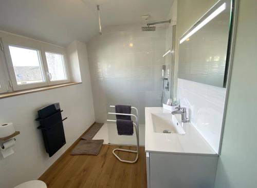 une salle de bain blanche avec un lavabo et un miroir dans l'établissement Maison à 250m de la plage la Grève Blanche avec WIFI à TREGASTEL - Réf 182, à Trégastel