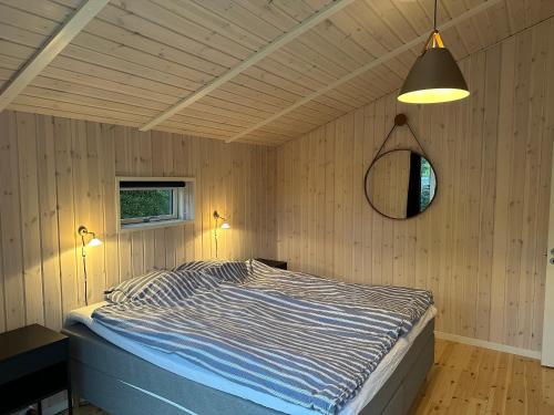 a bedroom with a bed and a mirror on the wall at Vejby Strand cabin near beach & Heatherhill - 101 m2 in Vejby