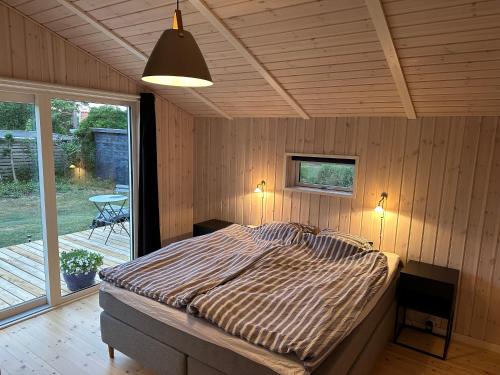 a bedroom with a bed in a room with a patio at Vejby Strand cabin near beach & Heatherhill - 101 m2 in Vejby