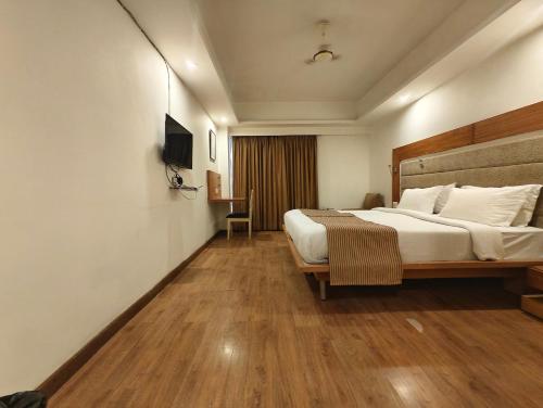 a hotel room with a bed and a television at The Sky Comfort, Ahmedabad in Ahmedabad