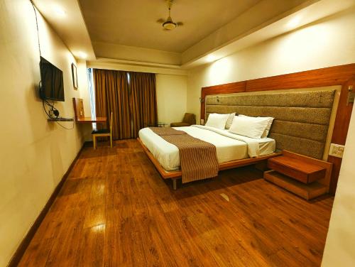a bedroom with a large bed and wooden floors at The Sky Comfort, Ahmedabad in Ahmedabad