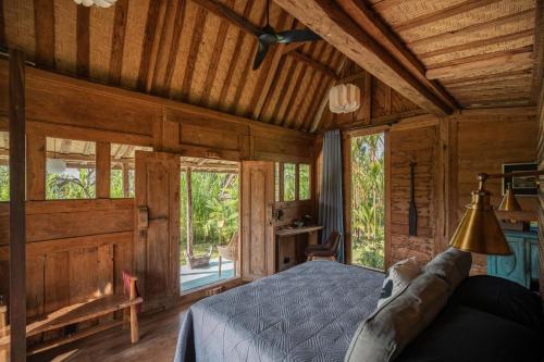 a bedroom with a bed in a room with windows at Desa Seni Baturiti in Baturiti