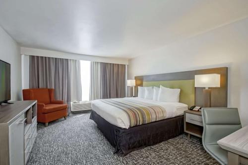 a hotel room with a bed and a chair at Country Inn & Suites by Radisson, New Orleans I-10 East, LA in New Orleans