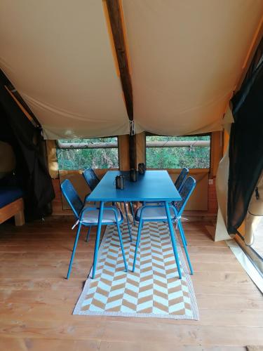 une table bleue et des chaises dans une tente dans l'établissement lodge Crusoé, à Beaumont-de-Lomagne