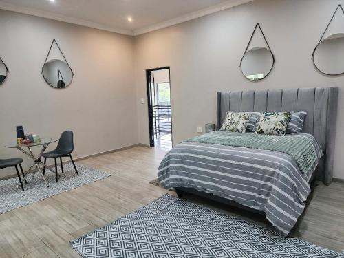 a bedroom with a bed and a table and mirrors at Eastern Road Executive Suites in Harare