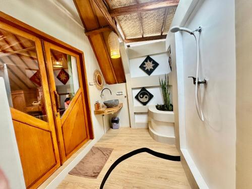 a bathroom with a toilet and a door and a rug at Sunny Rose Bungalows Gili Air - Adults only in Gili Air
