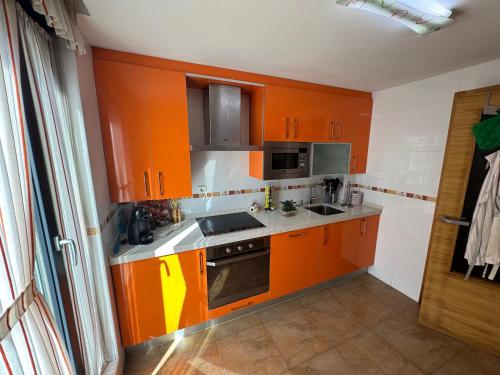 an orange kitchen with a sink and a stove at Chalet los Jardines in Polanco