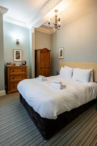 a bedroom with a large white bed and a dresser at The Lodge Harrogate in Harrogate