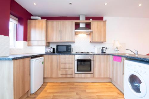 a kitchen with wooden cabinets and a washer and dryer at Durham 2-Bed Apartment in Durham