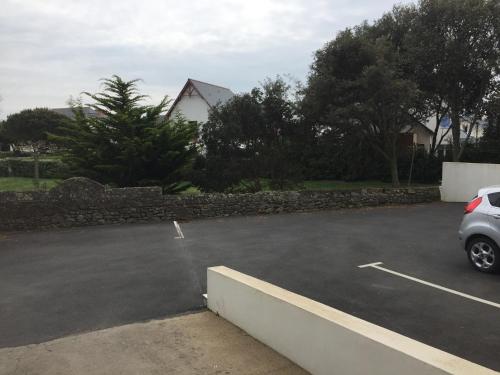 une voiture garée dans un parking à côté d'un mur de pierre dans l'établissement face mer et cote sauvage, au Croisic