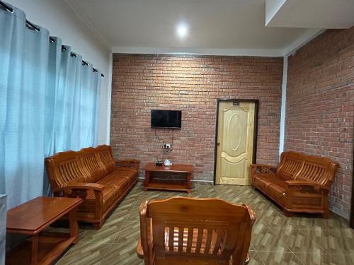 a living room with leather furniture and a brick wall at Kundasang Guesthouse in Kundasang