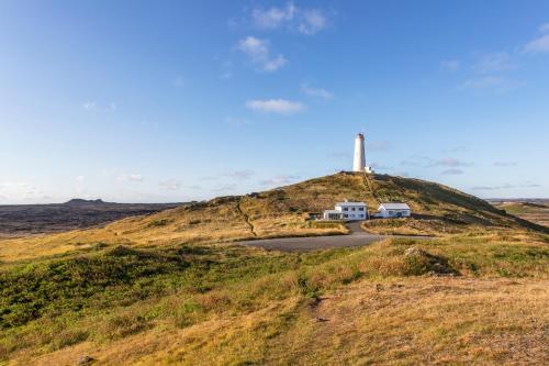 a house on top of a hill with a lighthouse at The Apartment at Reykjanesviti in Hafnir