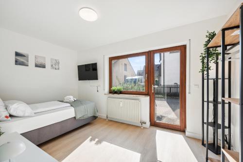 a white bedroom with a bed and a window at Sali Homes Weingenuss Eichbrunnen - Zentral in Obersulm