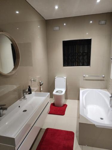 a bathroom with a sink and a toilet and a tub at Eastern Road Executive Suites in Harare