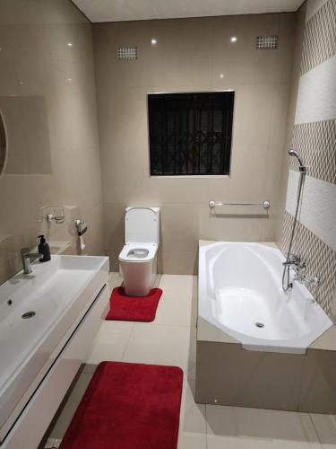 a bathroom with a tub and a toilet and a sink at Eastern Road Executive Suites in Harare