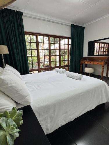 Un dormitorio con una cama blanca con cortinas verdes y un piano en Ben & Bern, en Krugersdorp