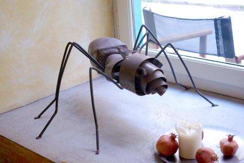 a metal spider is standing on a table next to apples at Amymone and Adiandi in Nafplio