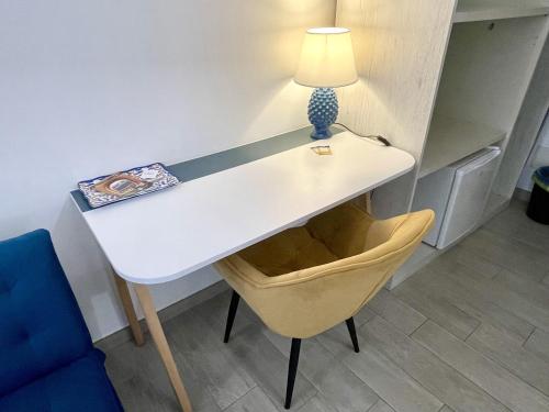 a white desk with a lamp and a yellow chair at I MORI - Holiday Rooms in Lascari