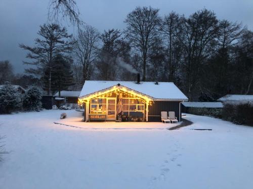 a log cabin with lights on it in the snow at Vejby Strand cabin near beach & Heatherhill - 101 m2 in Vejby