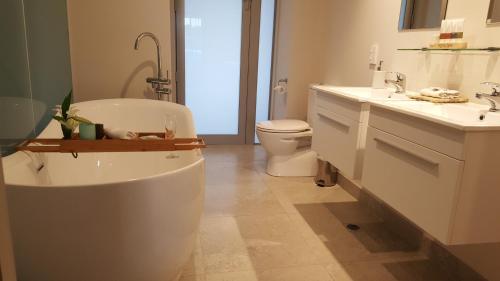 a bathroom with a tub and a sink and a toilet at Beach Pacific Apartments in Waihi Beach