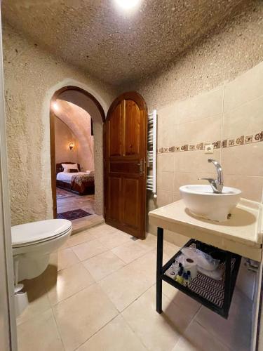 a bathroom with a sink and a toilet and a bed at Gedik Cave Hotel in Goreme