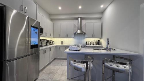 a kitchen with a refrigerator and two bar stools at French Style Mansion In Prestigious Angus Glen Markham in Markham