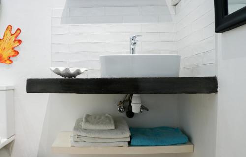 Un baño con lavabo y estante con toallas. en Louise by the Sea, en Grand Baie