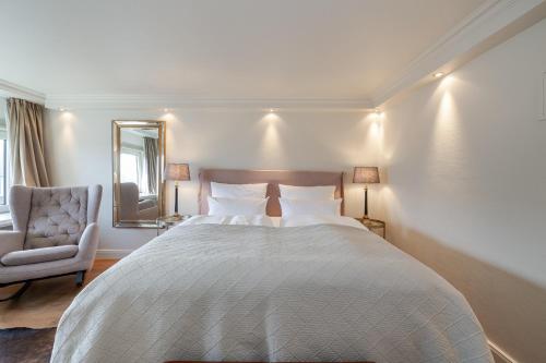 a bedroom with a bed and a chair and a mirror at Strönhof Kampen in Kampen
