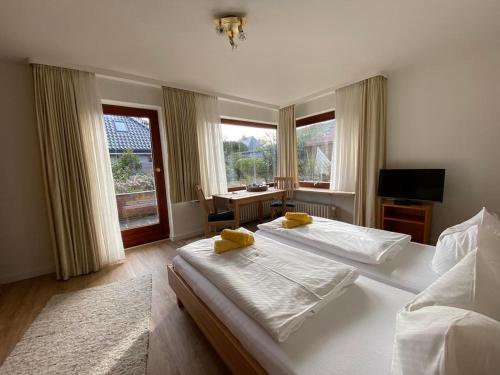 a bedroom with two beds and a desk and windows at Stockrosenhuus in Westerland
