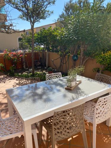 une table blanche et des chaises sur une terrasse dans l'établissement Maison à deux pas de la plage, au Barcarès