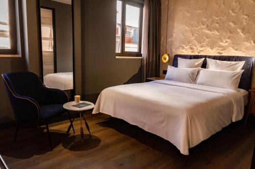 a bedroom with a large white bed and a chair at Letoh Letoh Sevilla in Seville