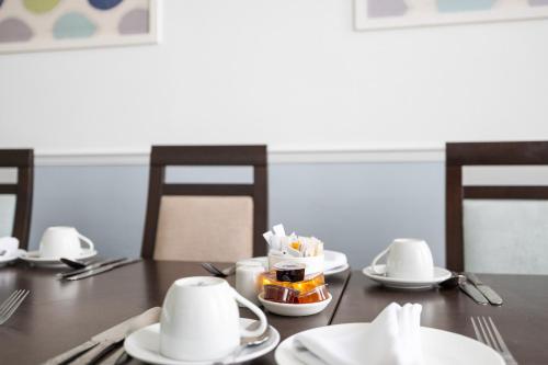 a wooden table with white plates and utensils on it at Imperial Plymouth in Plymouth