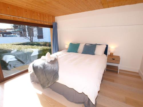 une chambre avec un grand lit et une grande fenêtre dans l'établissement Chamonix Centre - Sophisticated 2-Bedroom Duplex, à Chamonix-Mont-Blanc