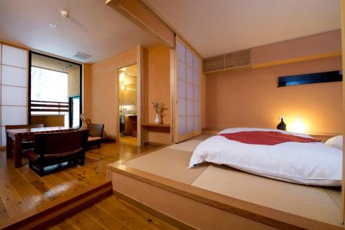 a bedroom with a bed and a desk and a table at Onsen Ryokan Yamaki in Nasushiobara