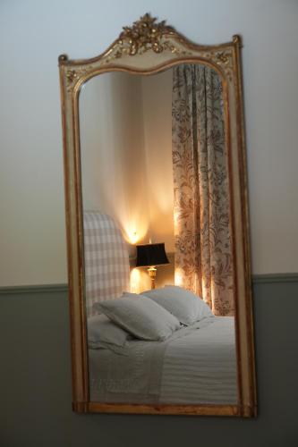 a mirror reflecting a bed with a chair and a lamp at Villino di Porporano in Parma